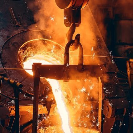 Pouring bright liquid iron or metal with sparks into container in steel mill or workshop blast furnace foundry. Metal casting process in metallurgical plant.